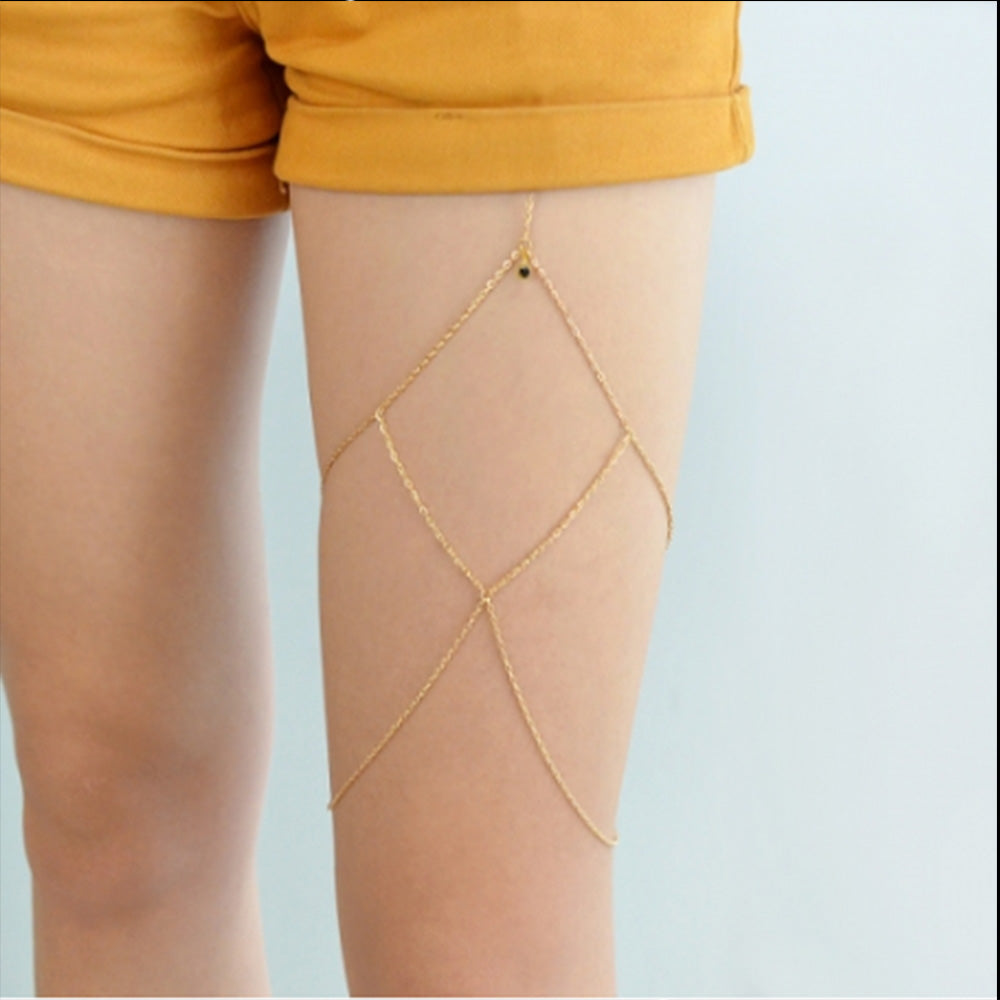 Woman wearing the gold Kelabu diamond detail leg chain underneath yellow shorts