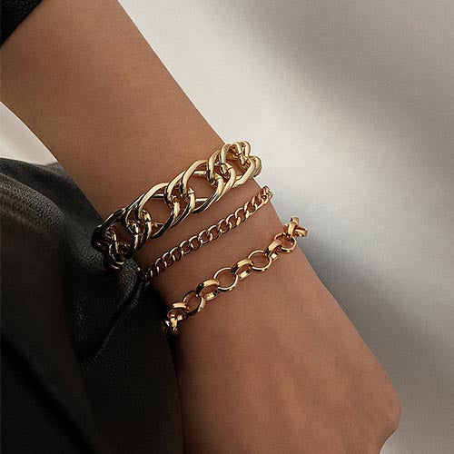 person wearing three gold chain bracelets including chunky and dainty