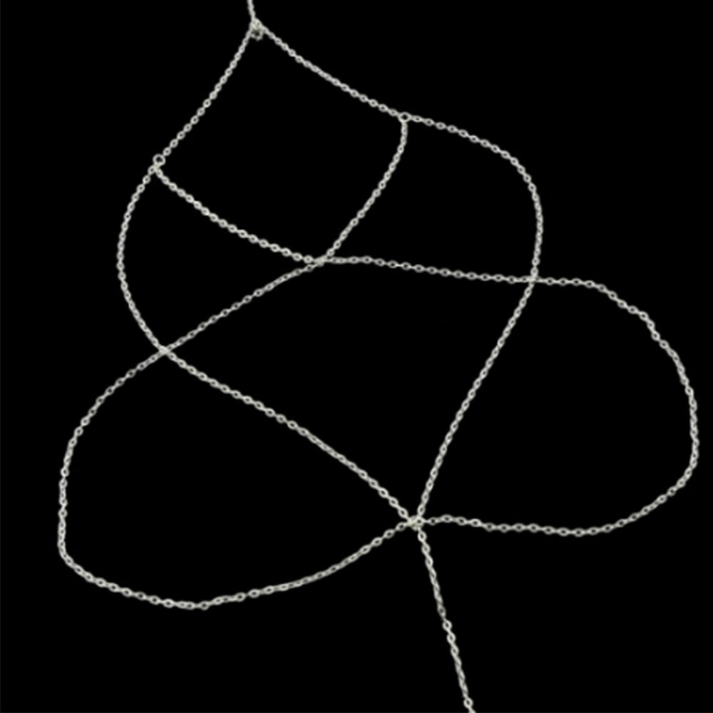 The Kelabu diamond detail leg chain in silver laid out flat on a black background