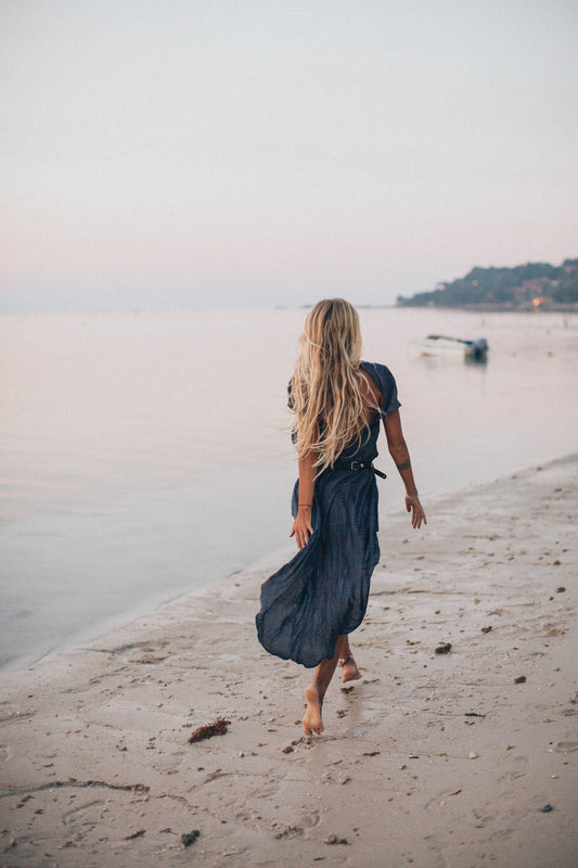 Woman barefoot on the beach wearing a spring capsule wardrobe piece - a midi dress 