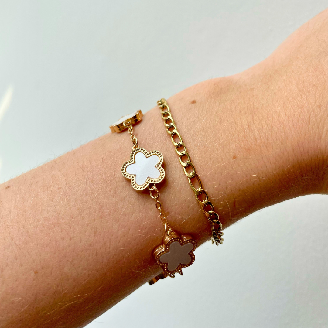 person wearing gold figaro dainty chain bracelet with white and gold clover bracelet