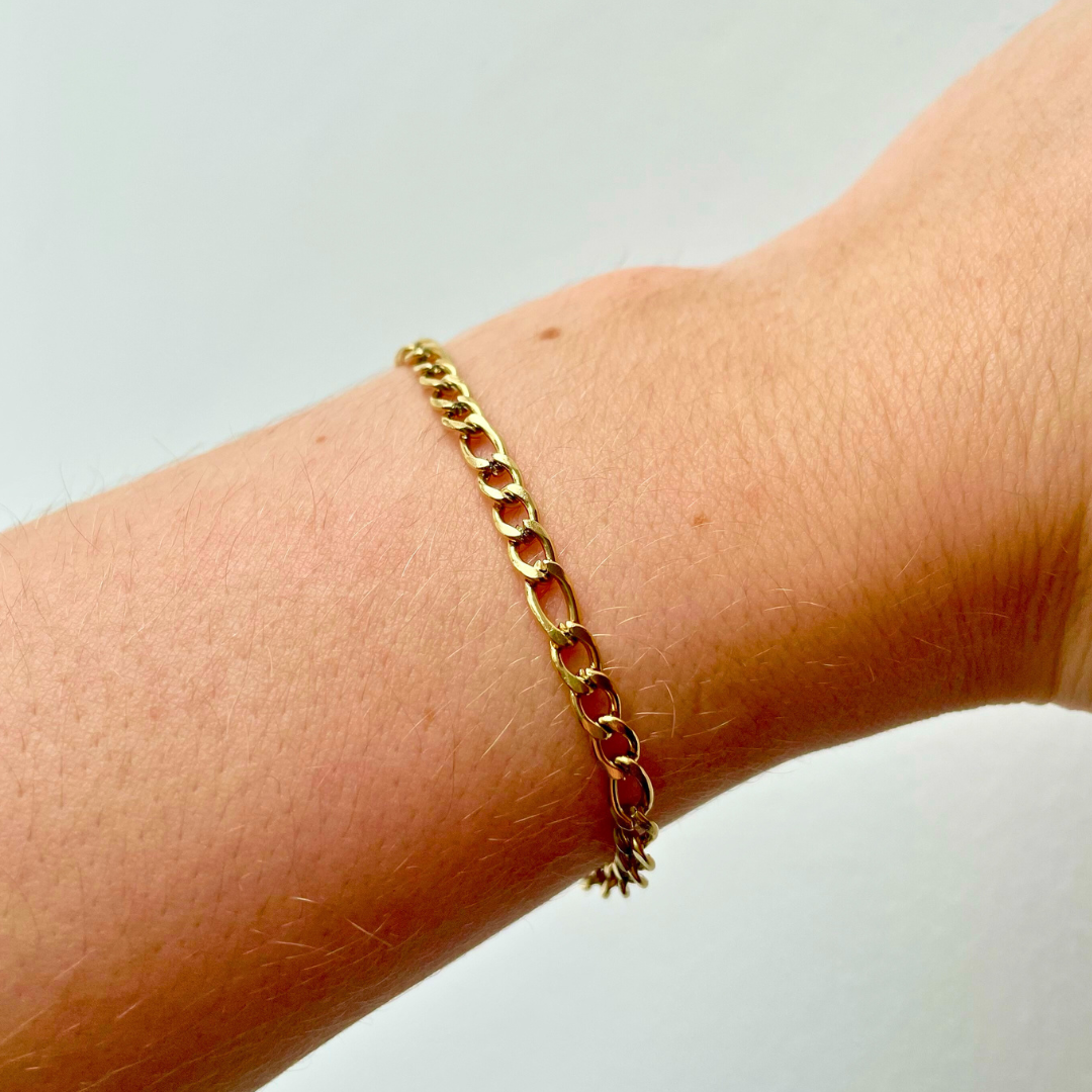 close up of person wearing dainty gold figaro chain bracelet