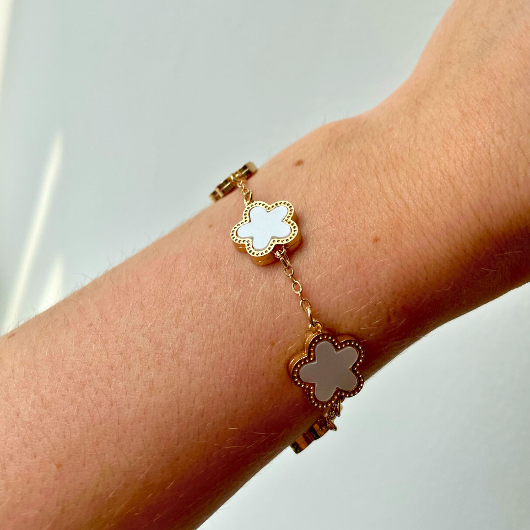 close up of person wearing gold and white clover dainty flower charm bracelet