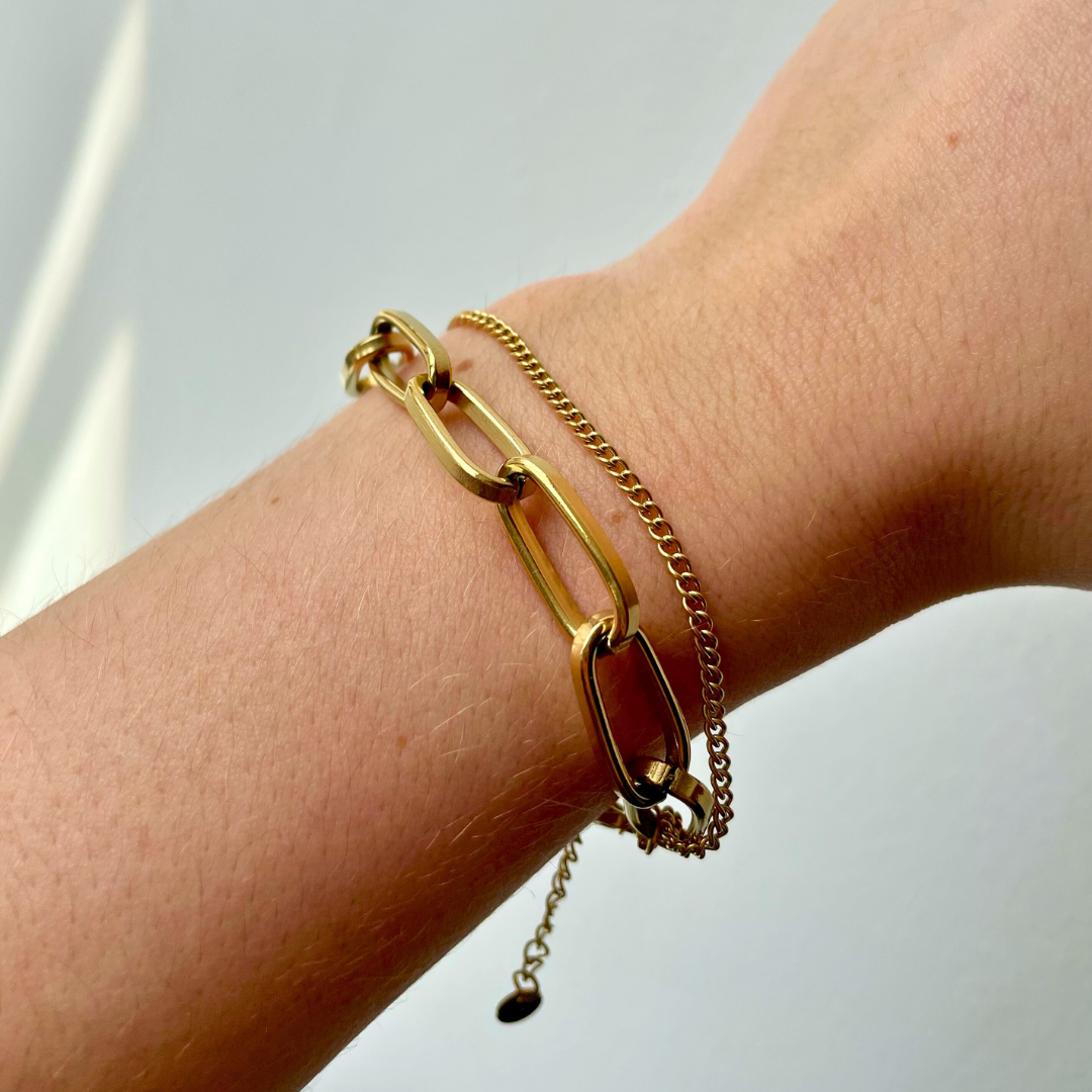 person wearing gold layered chain bracelet with one dainty chain and one chunky chain