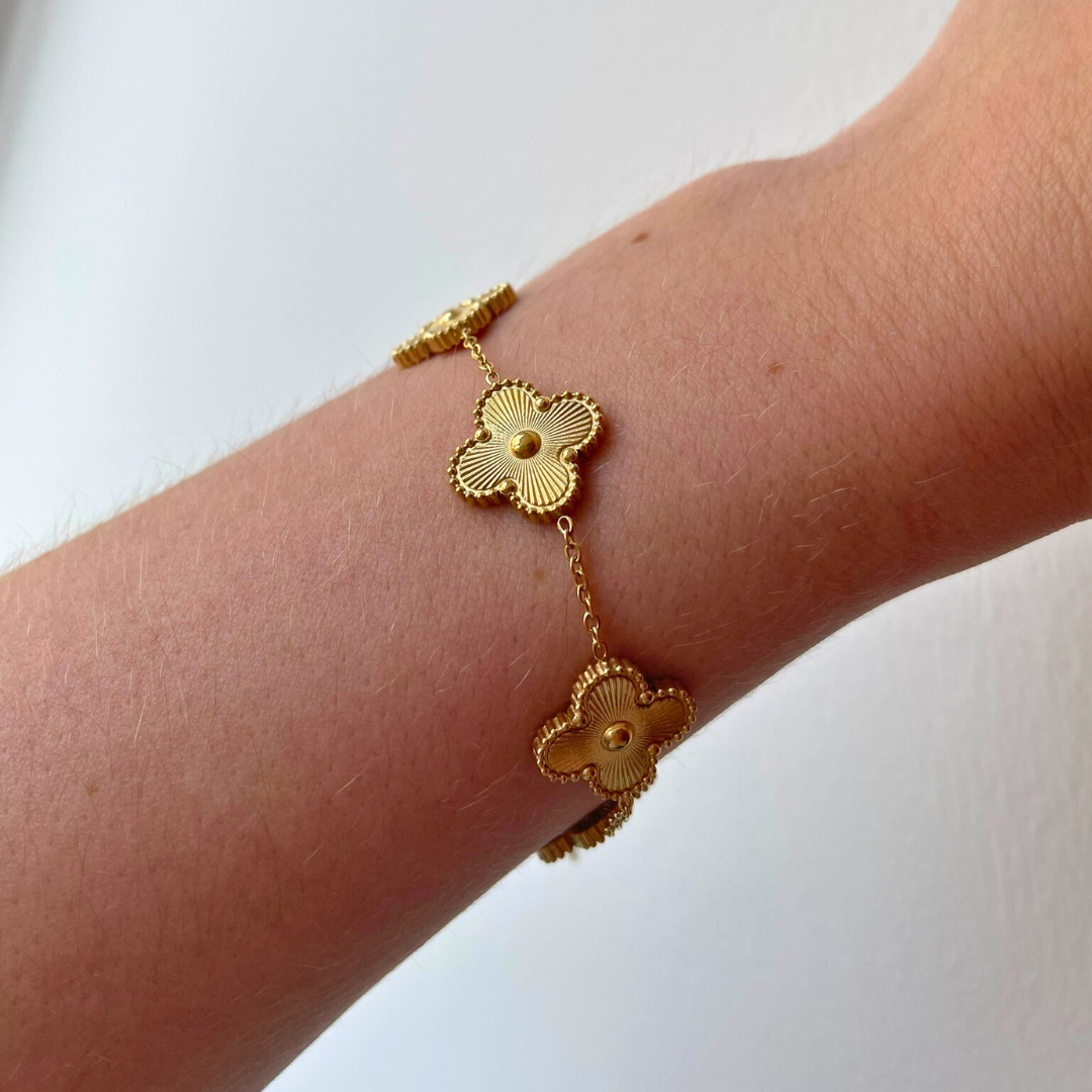 person wearing gold flower charm bracelet