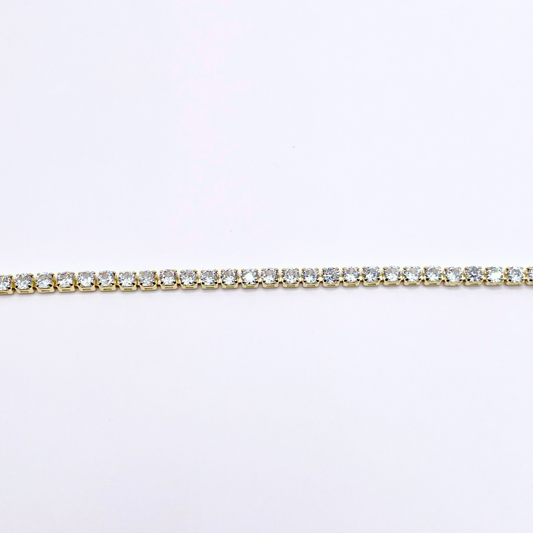 close up of detail on dainty gold tennis bracelet