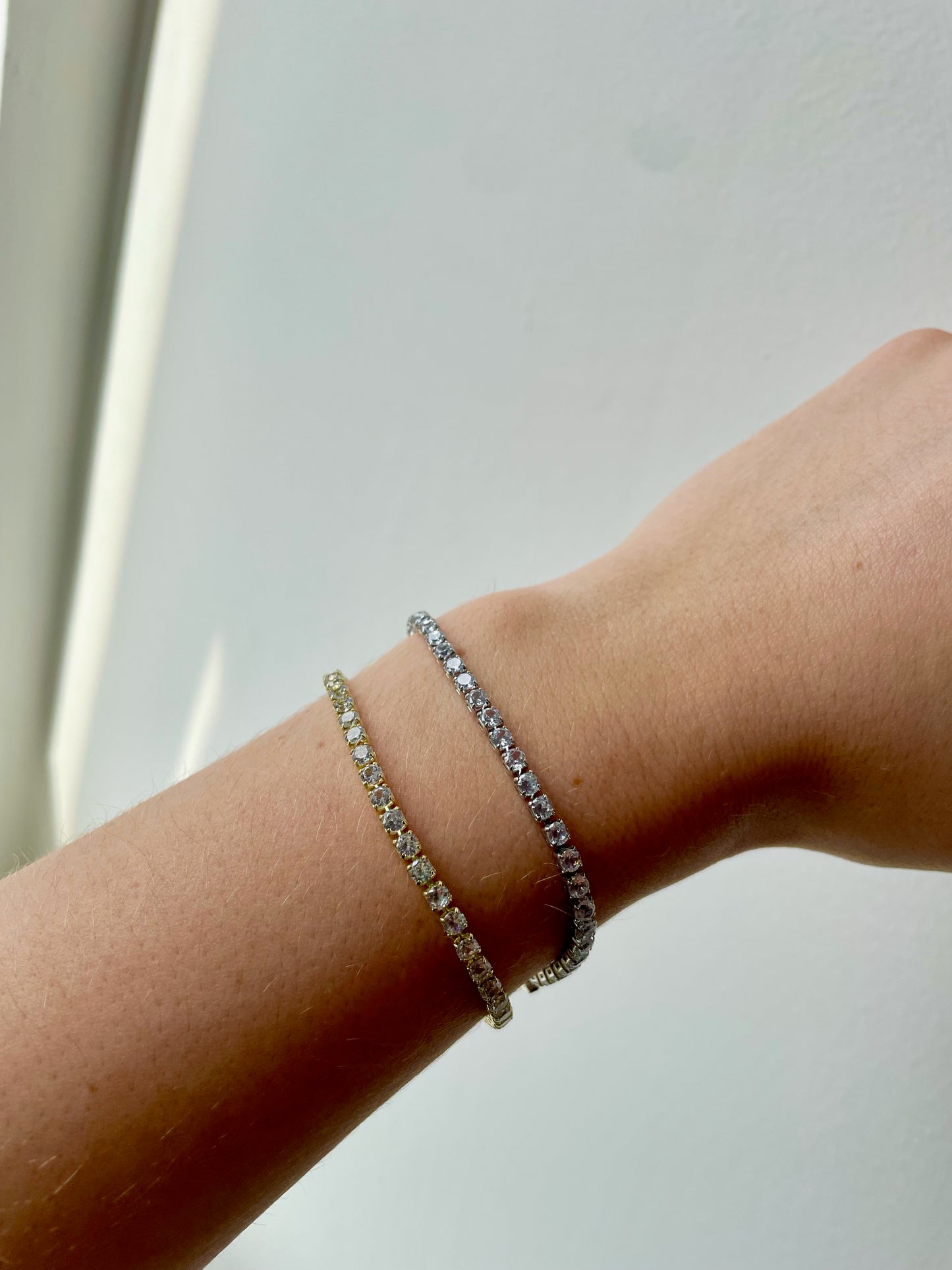 person wearing both silver and gold cubic zirconia dainty tennis bracelet