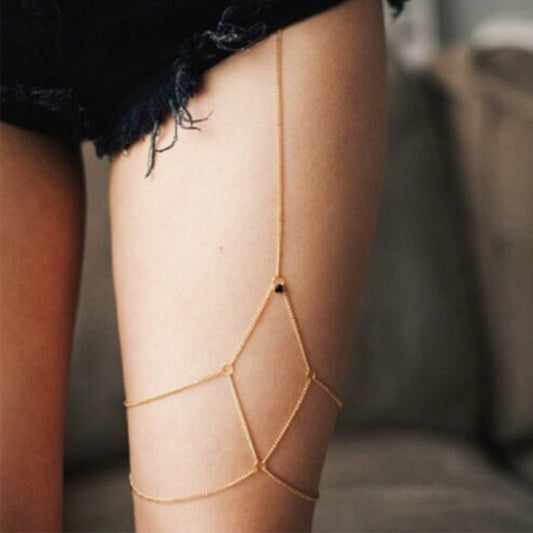 Woman wearing the gold Kelabu diamond detail leg chain underneath ripped black denim shorts