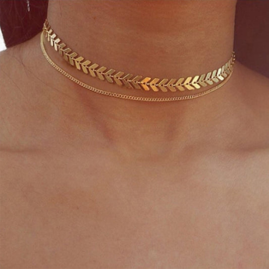 A woman wearing the Kelabu gold choker necklace which features two different designs and is multi layered