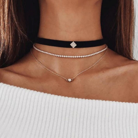 The stylish layered choker from Kelabu, with velvet, gold and crystal designs, being worn by a woman with long brown hair and wearing an off the shoulder white jumper 